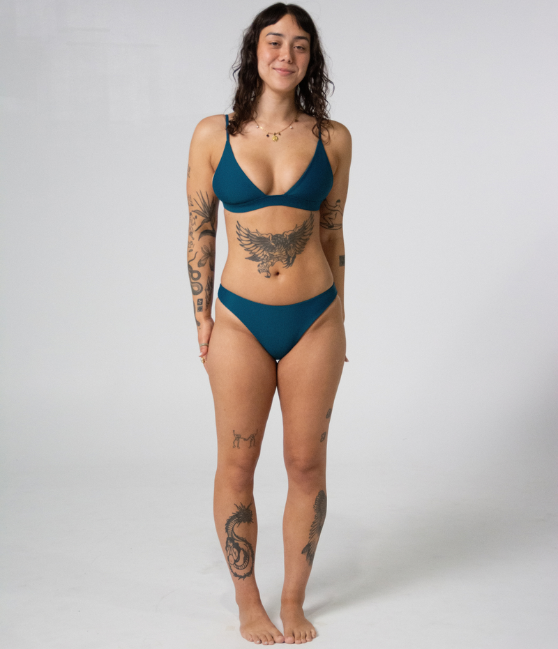 Byron Low Rise Bottoms in Peacock (teal), front view on model with hands behind her back