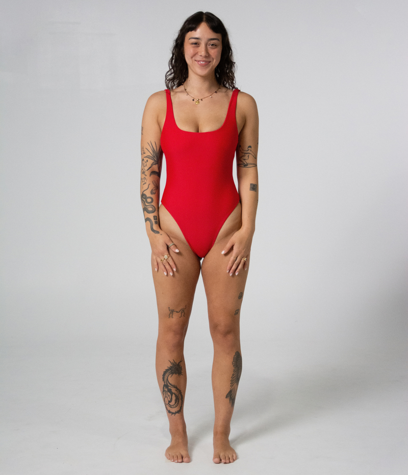Mali One Piece in Scarlet (red), front view on model with hands on thighs, showing the square neckline