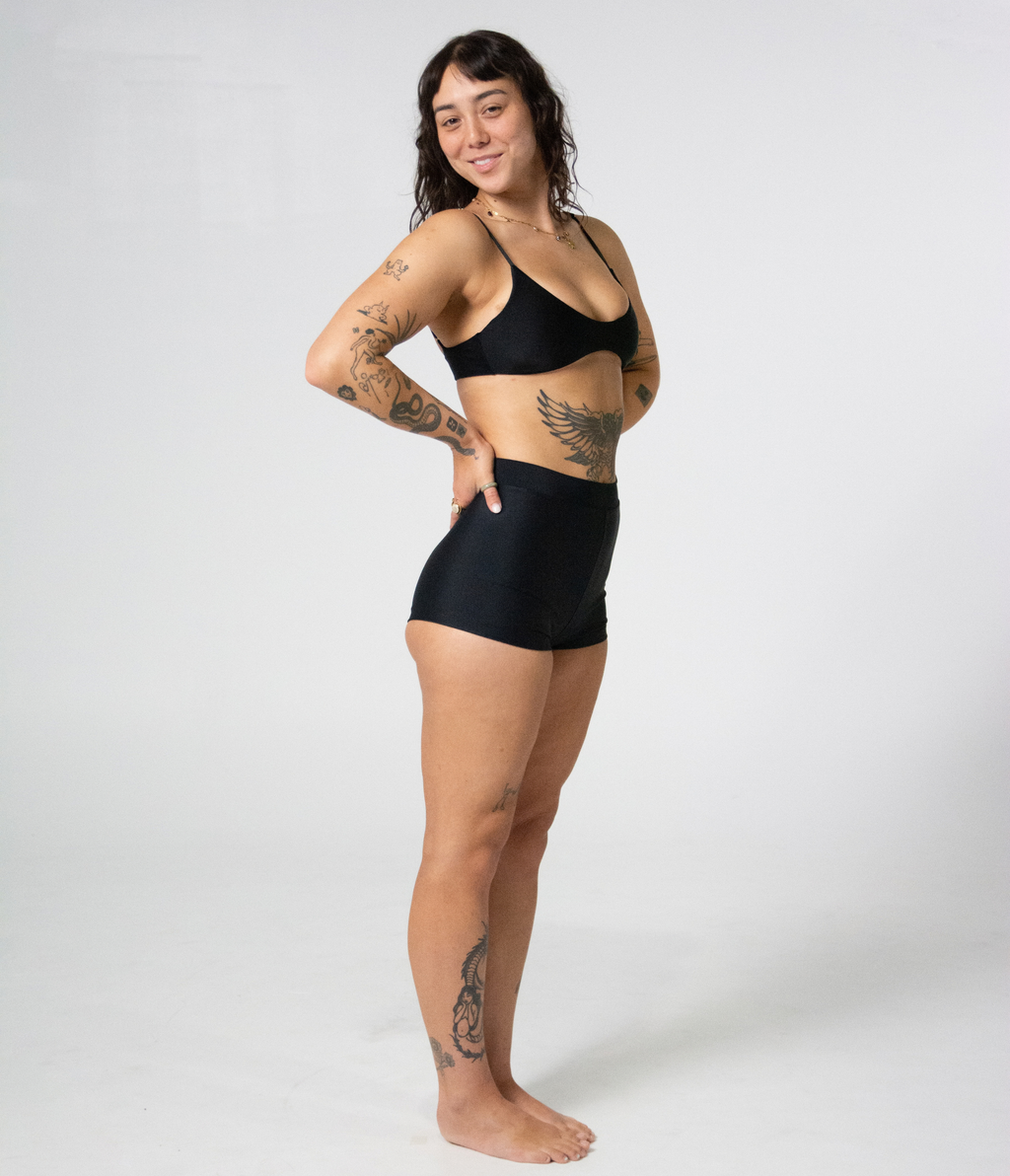 Crescent Scoop Top in Noir (black), right side view on model with hands at her sides