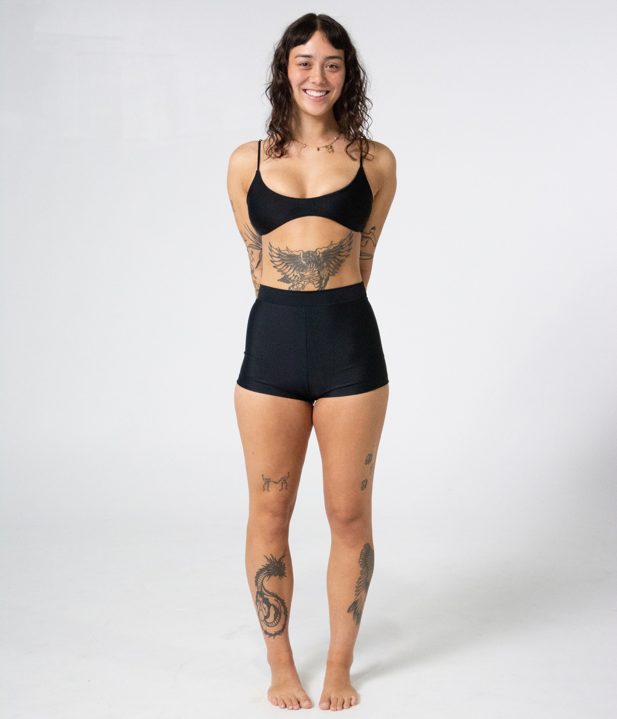 Burleigh Swim Shorts in Noir (black), front view on model with hands behind her back