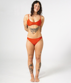 Byron Low Rise Bottoms in Rust (orange), front view on model with hands behind her back