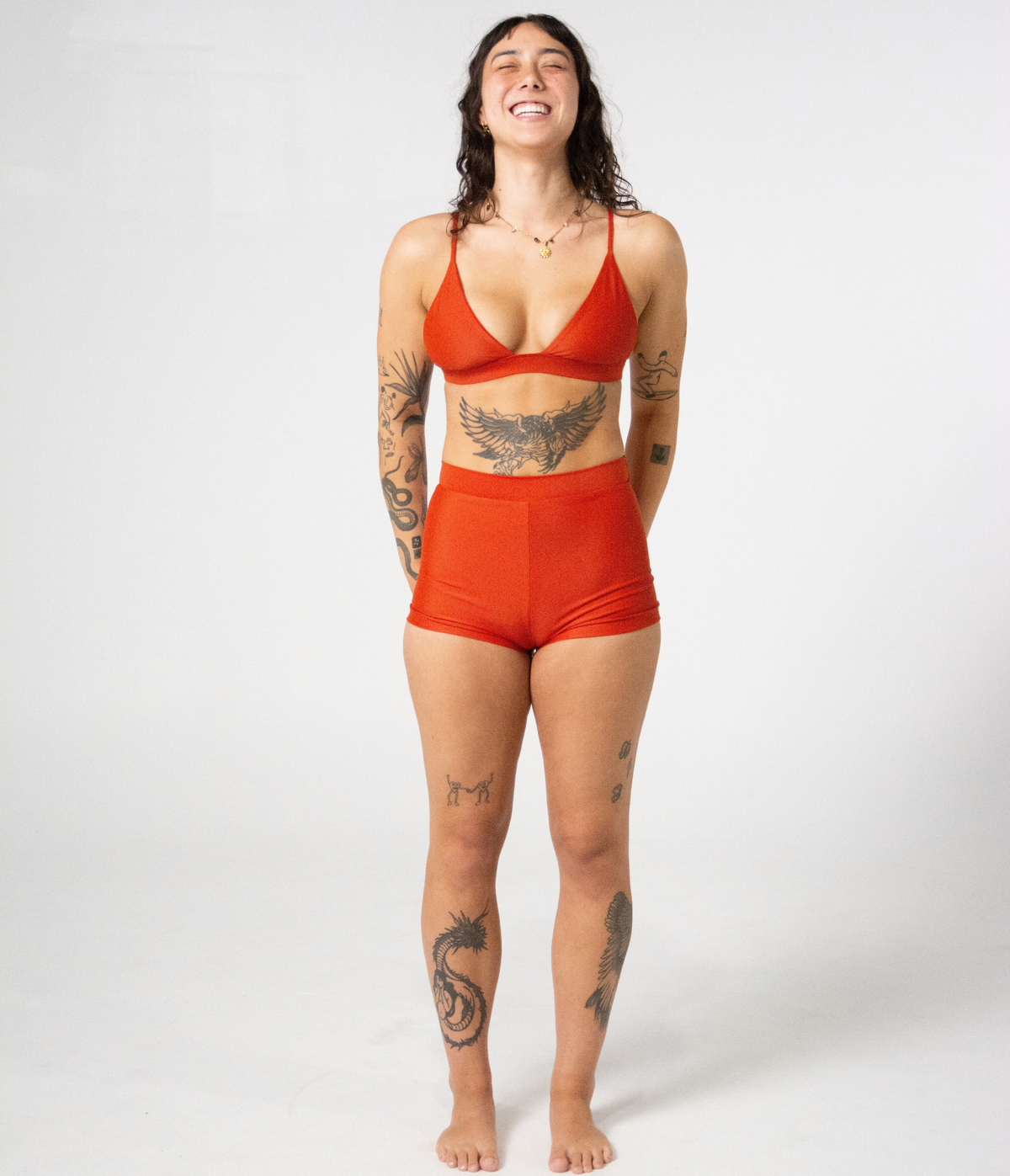 Kirra Triangle Top in Rust (orange), front view on model with hands behind her back
