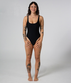 Mali One Piece in Noir (black), front view on model with hands on thighs, showing the square neckline