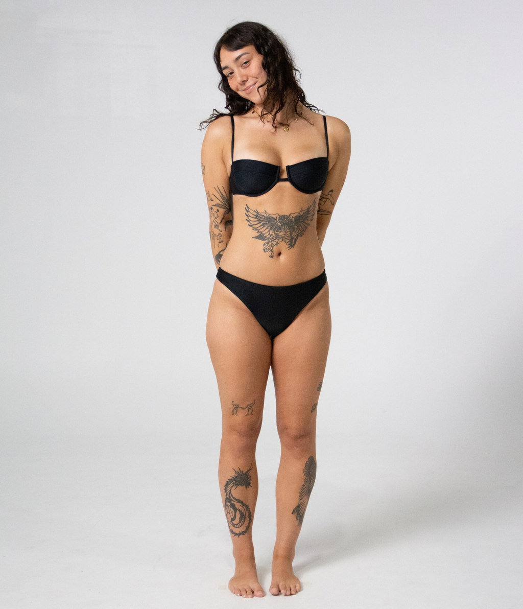 Byron Low Rise Bottoms in Noir (black), front view on model with hands behind her back