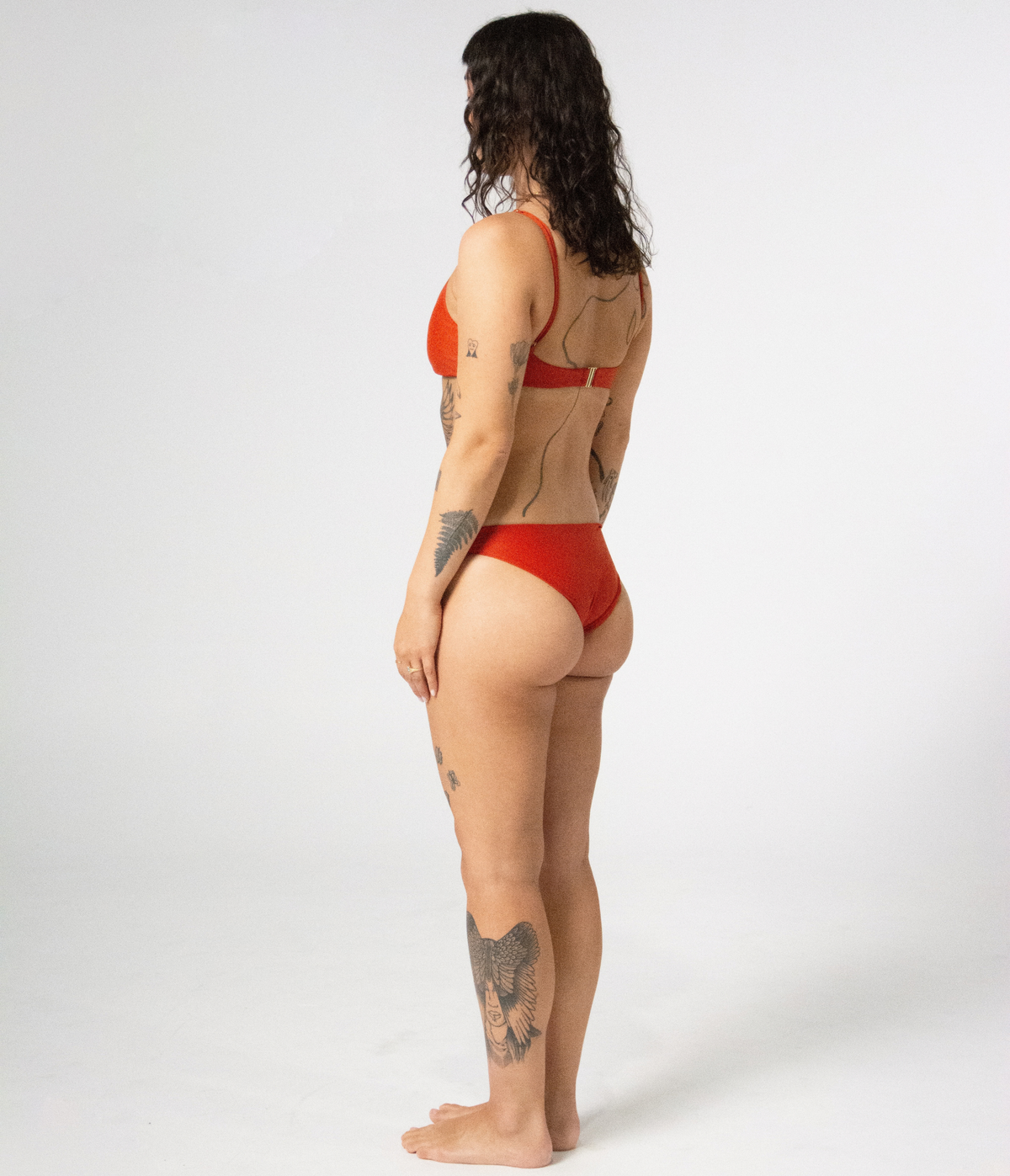 Crescent Scoop Top in Rust (orange), left side view on model